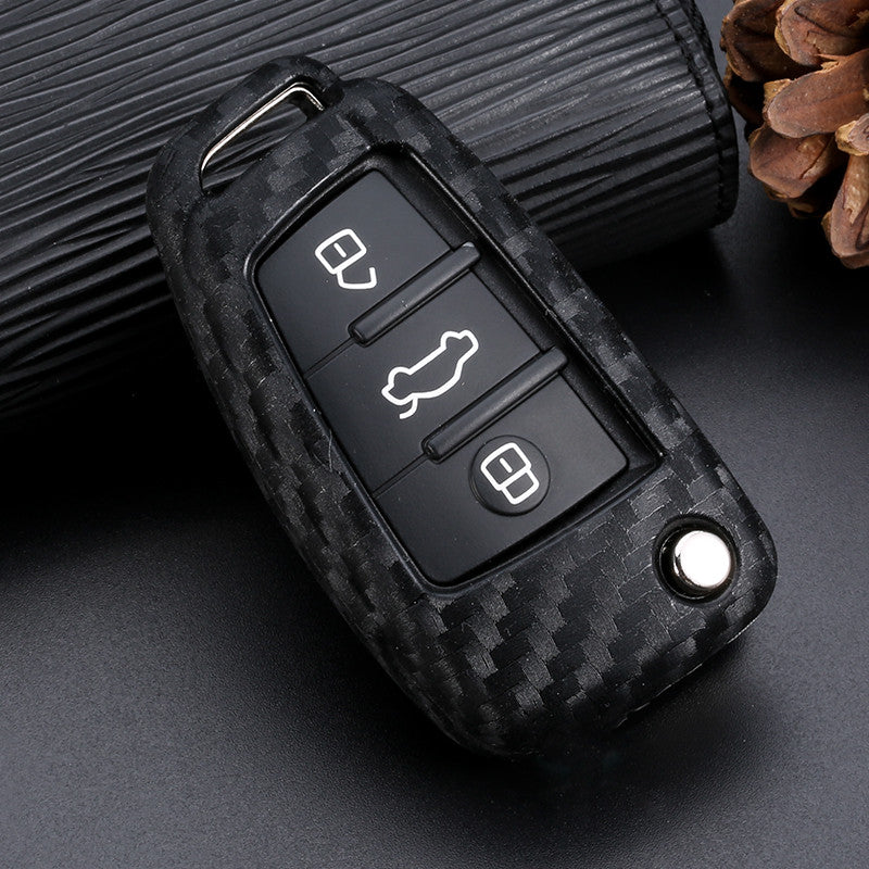 Carbon fiber patterned car key fob cover with silicone texture placed on a dark surface