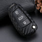 Carbon fiber patterned car key fob cover with silicone texture placed on a dark surface