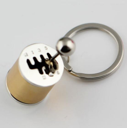 Gold mini gear shift keychain with a metallic design on a white background
